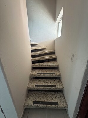Eine Treppe mit strukturierter Oberfläche, die nach oben führt, mit einem kleinen Fenster am oberen Ende.