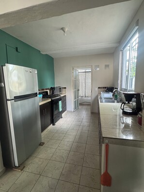 A kitchen with a refrigerator, stove, microwave, and sink. - Casa de Familia (Puerto Vallarta)