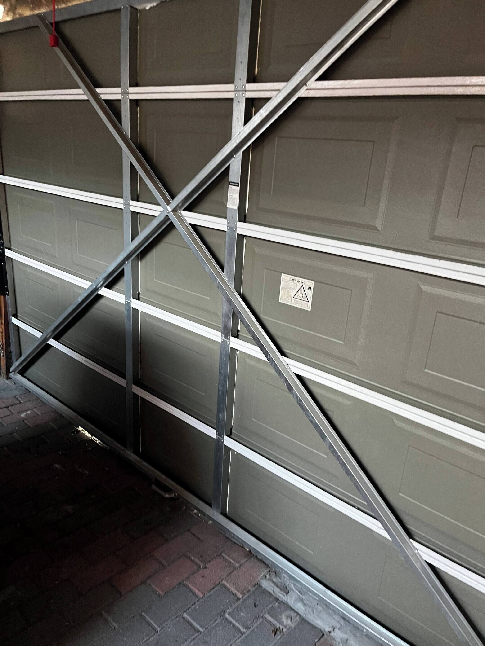 A garage door with a warning sign, metal support beams, and a brick floor.