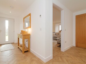 Een kamer met een houten vloer, een witte deur, een spiegel, een klein houten kastje en een lamp.