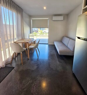 A modern living space with a dining area, a sofa, and a refrigerator. - Kernel Retreat
Relax in our tranquil guest house and dedicated car park. (Jack's Point)