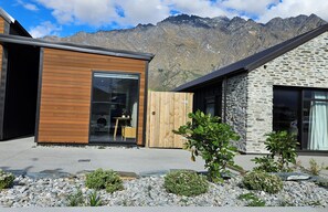 A modern building with a wooden exterior and a stone facade, set against a mountainous backdrop. - Kernel Retreat
Relax in our tranquil guest house and dedicated car park. (Jack's Point)