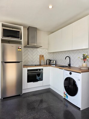 A modern kitchen with stainless steel appliances, a built-in oven, and a washing machine. - Kernel Retreat
Relax in our tranquil guest house and dedicated car park. (Jack's Point)