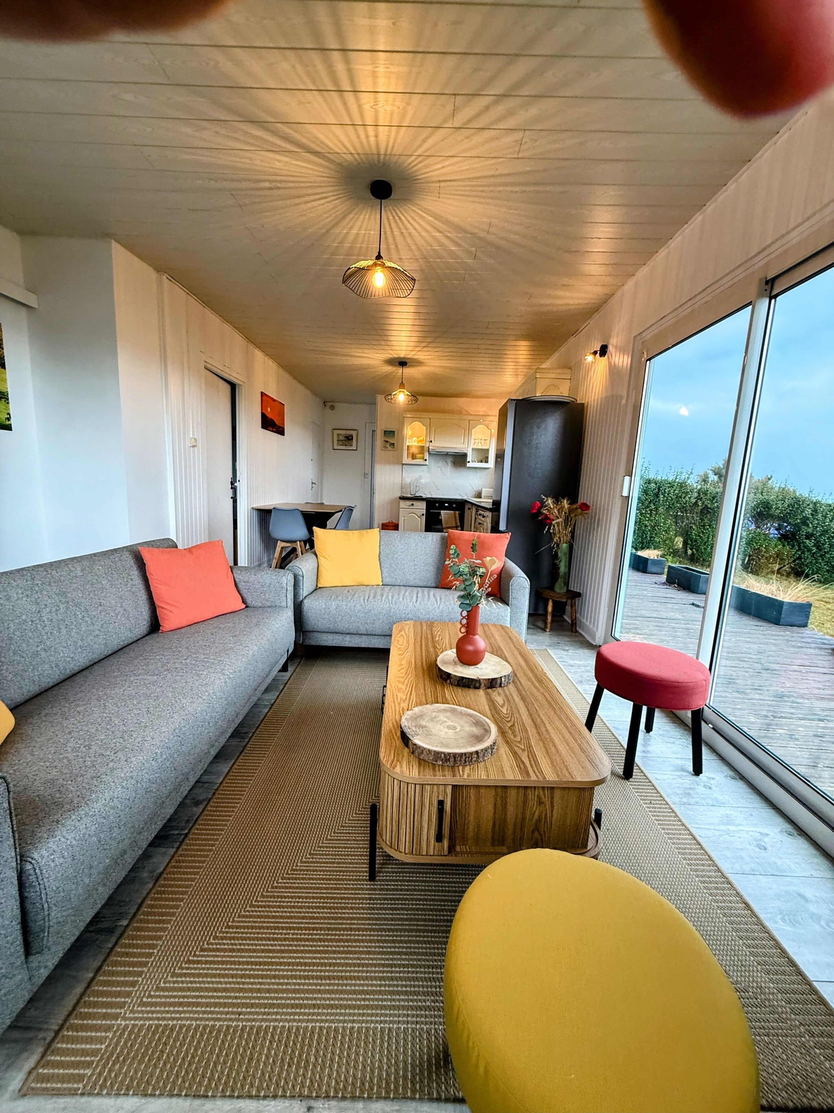 A modern living room with a sofa, a coffee table, and a red stool.