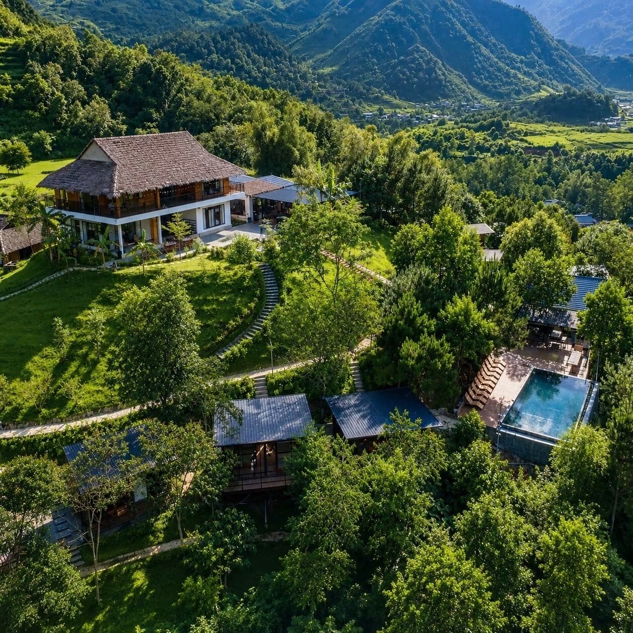 A large house with a thatched roof and a swimming pool surrounded by lush greenery and mountains.