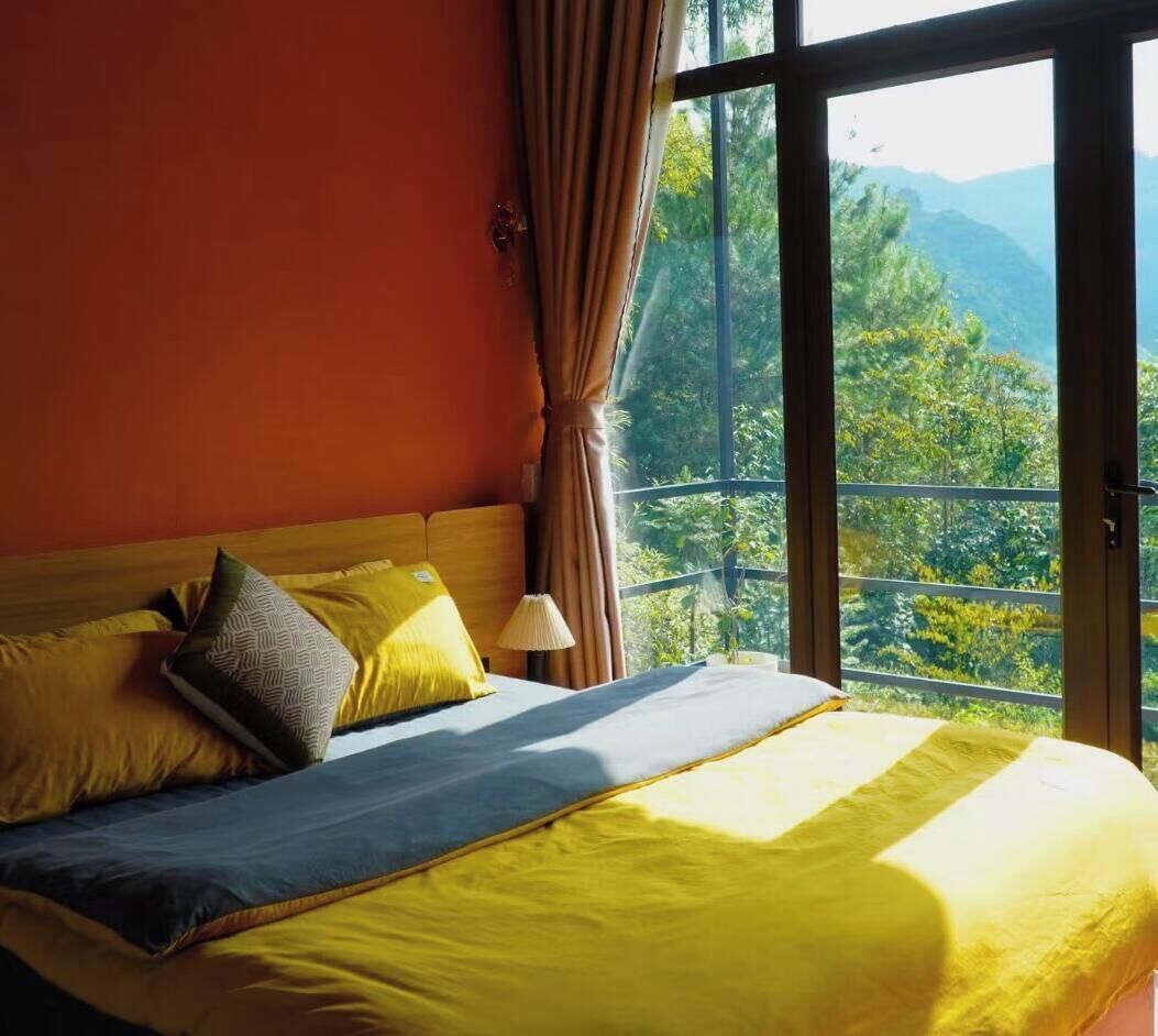 Un letto con vista su un paesaggio montuoso attraverso ampie finestre.