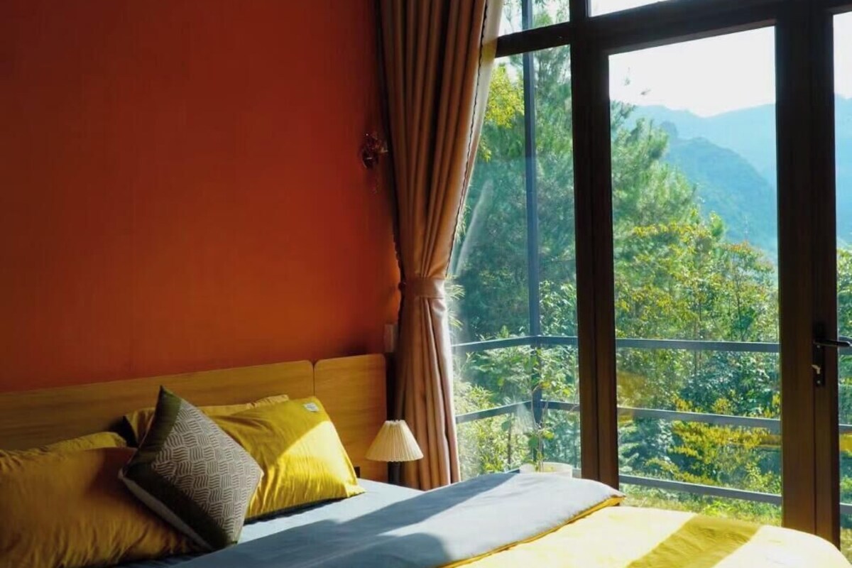 Una cama con vista a un paisaje montañoso a través de amplios ventanales.