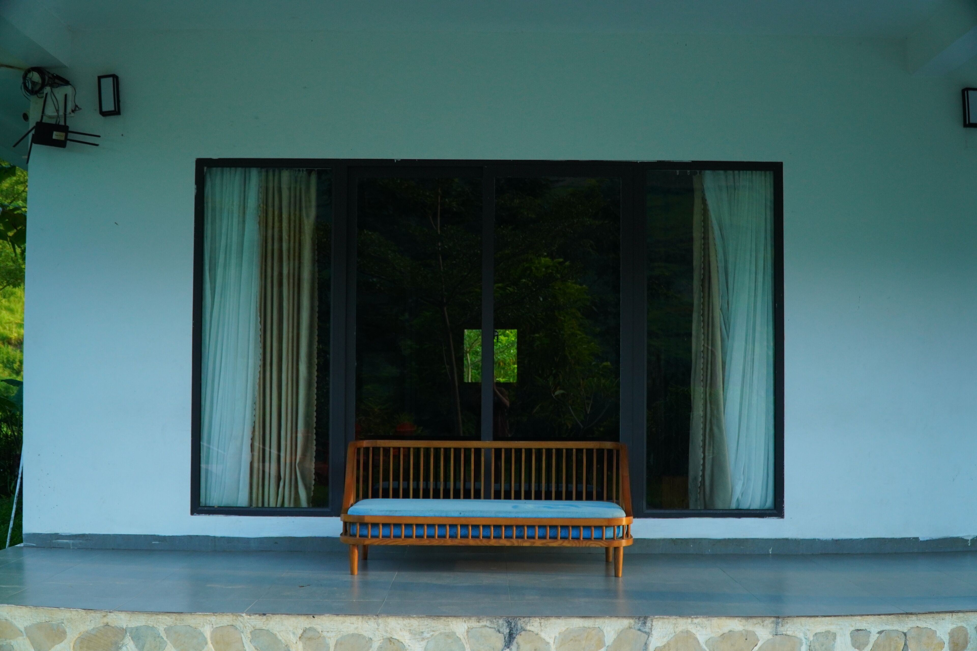A bench in front of a building with large windows and a stone base.