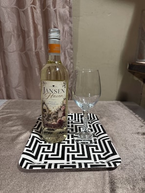 Una botella de vino Jansen Haven y una copa vacía sobre un mantel estampado.
