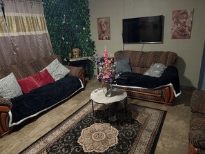 A living room with a sofa, armchair, coffee table, and a decorative wall with a flat-screen TV.