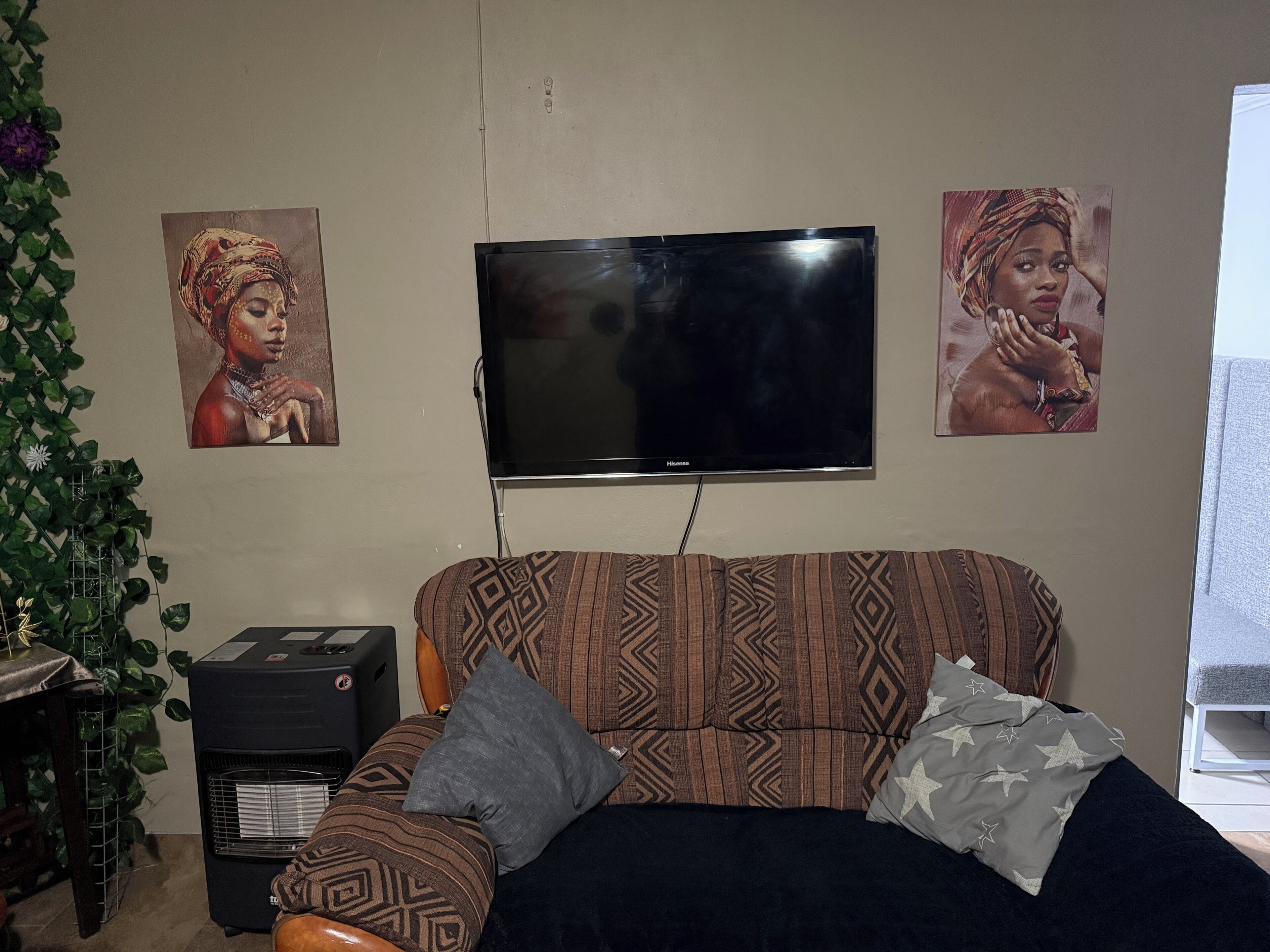 Ein Wohnzimmer mit einem gemusterten Sofa, einem Flachbildfernseher und zwei an der Wand befestigten Bildern.