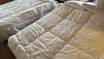 Quarto com duas camas, cada uma com roupa de cama e almofadas brancas.