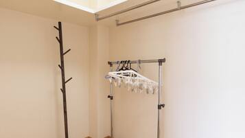 A room with a wooden floor, a coat rack, and a metal drying rack.
