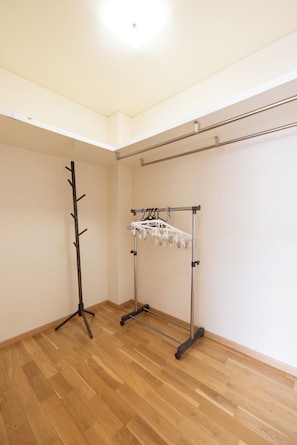 Una habitación con piso de madera, un perchero y un tendedero de metal.
