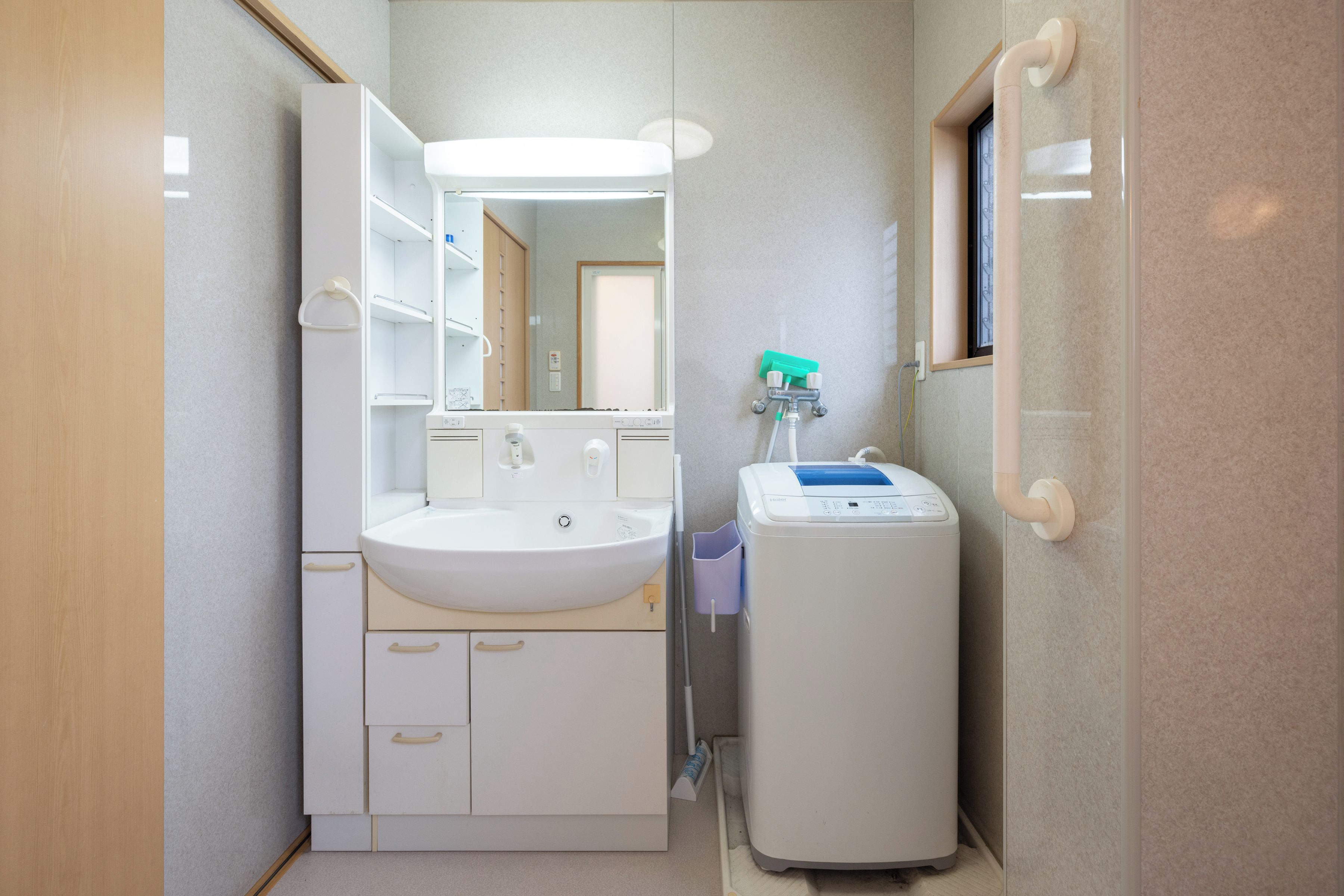 A bathroom with a white sink, mirror, and a handheld showerhead.