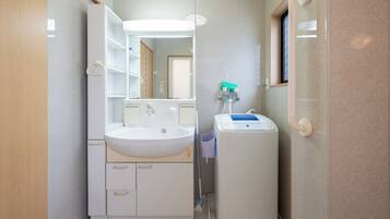A bathroom with a white sink, mirror, and a handheld showerhead.