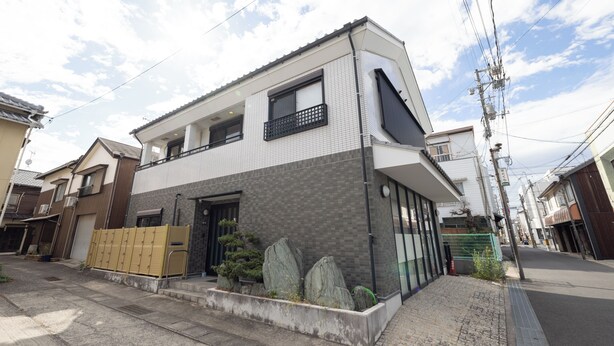 Ein zweigeschossiges Wohngebäude mit modernem Design, mit Balkon, großen Fenstern und einer Klinkerapassade.