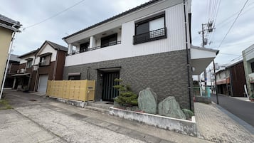 Um edifício residencial moderno de dois andares com fachada em azulejos, varanda e portão.