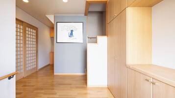 A hallway with wooden flooring, a framed artwork on the wall, and a traditional sliding door.