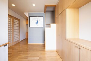 A hallway with wooden flooring, a framed artwork on the wall, and a traditional sliding door.