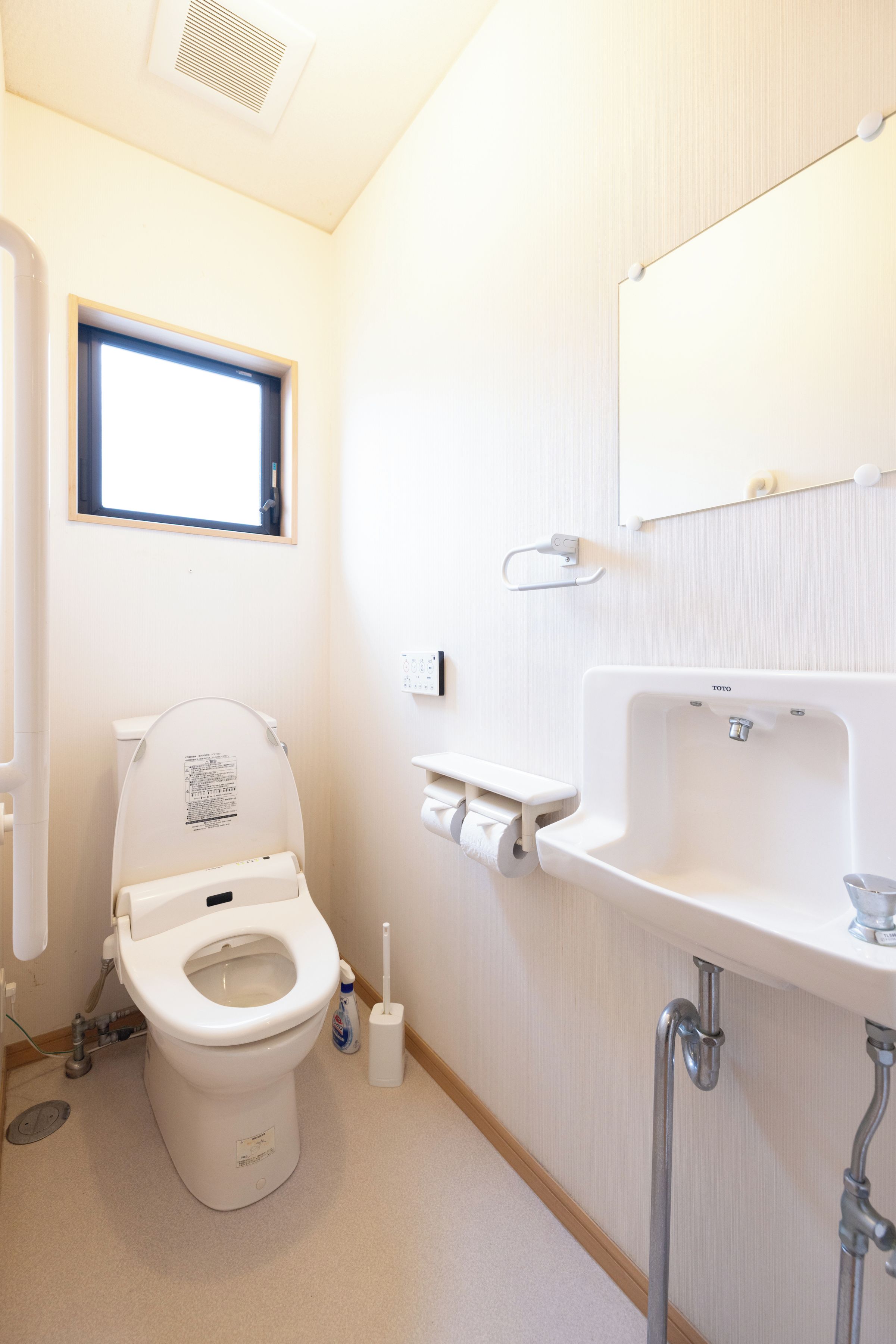 A bathroom with a toilet, a sink, and a window.