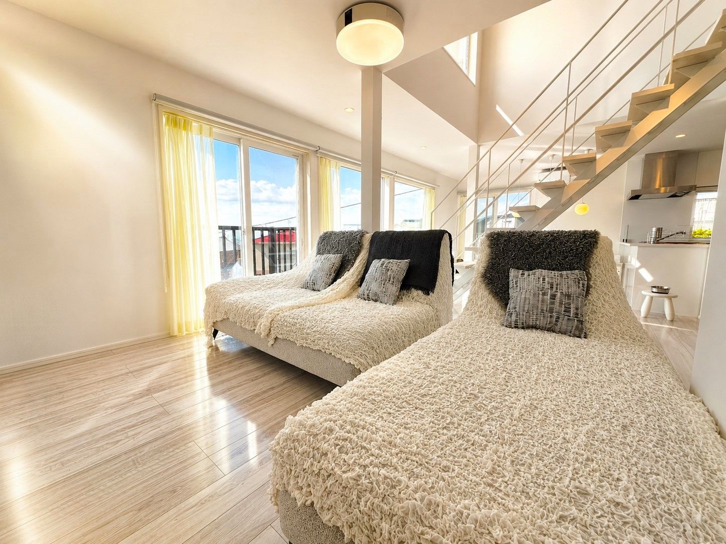 Une chambre moderne avec deux lits, un balcon et un coin cuisine.