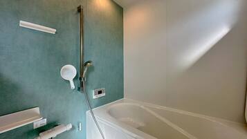 Un baño con bañera, cabezal de ducha manual, grifo empotrado, lavamanos portátil y un inodoro.