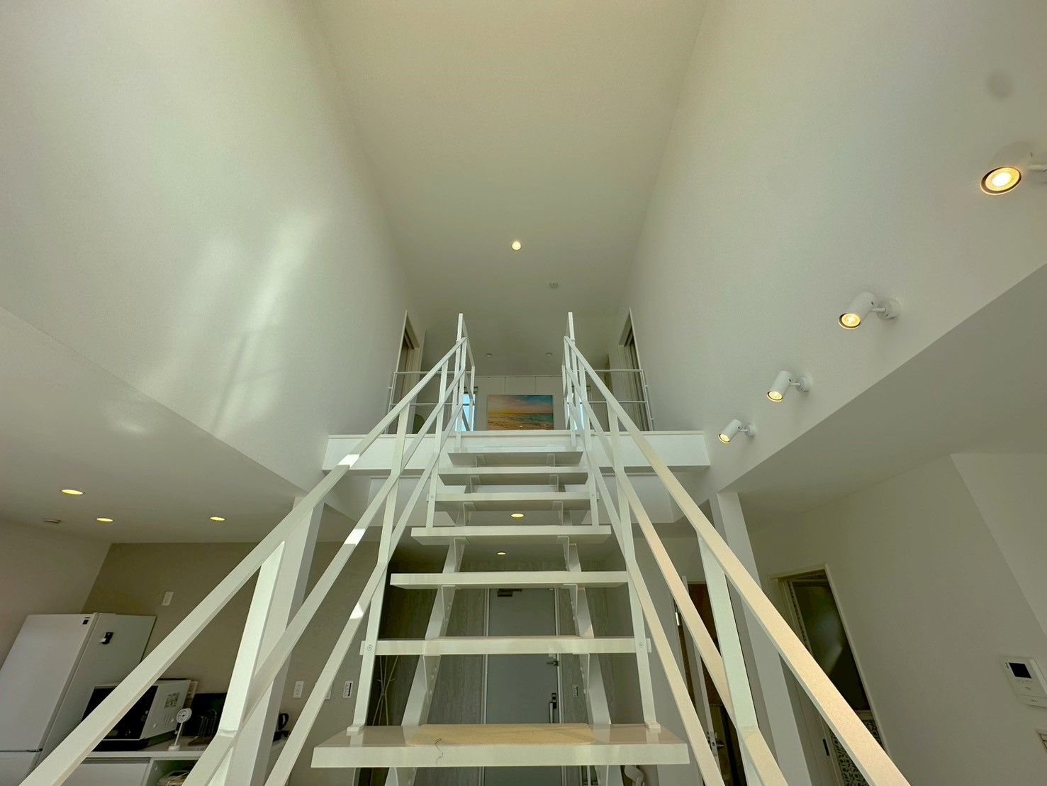 A modern interior with a central staircase, white walls, and recessed lighting.