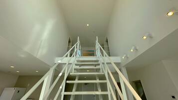 A modern interior with a central staircase, white walls, and recessed lighting.