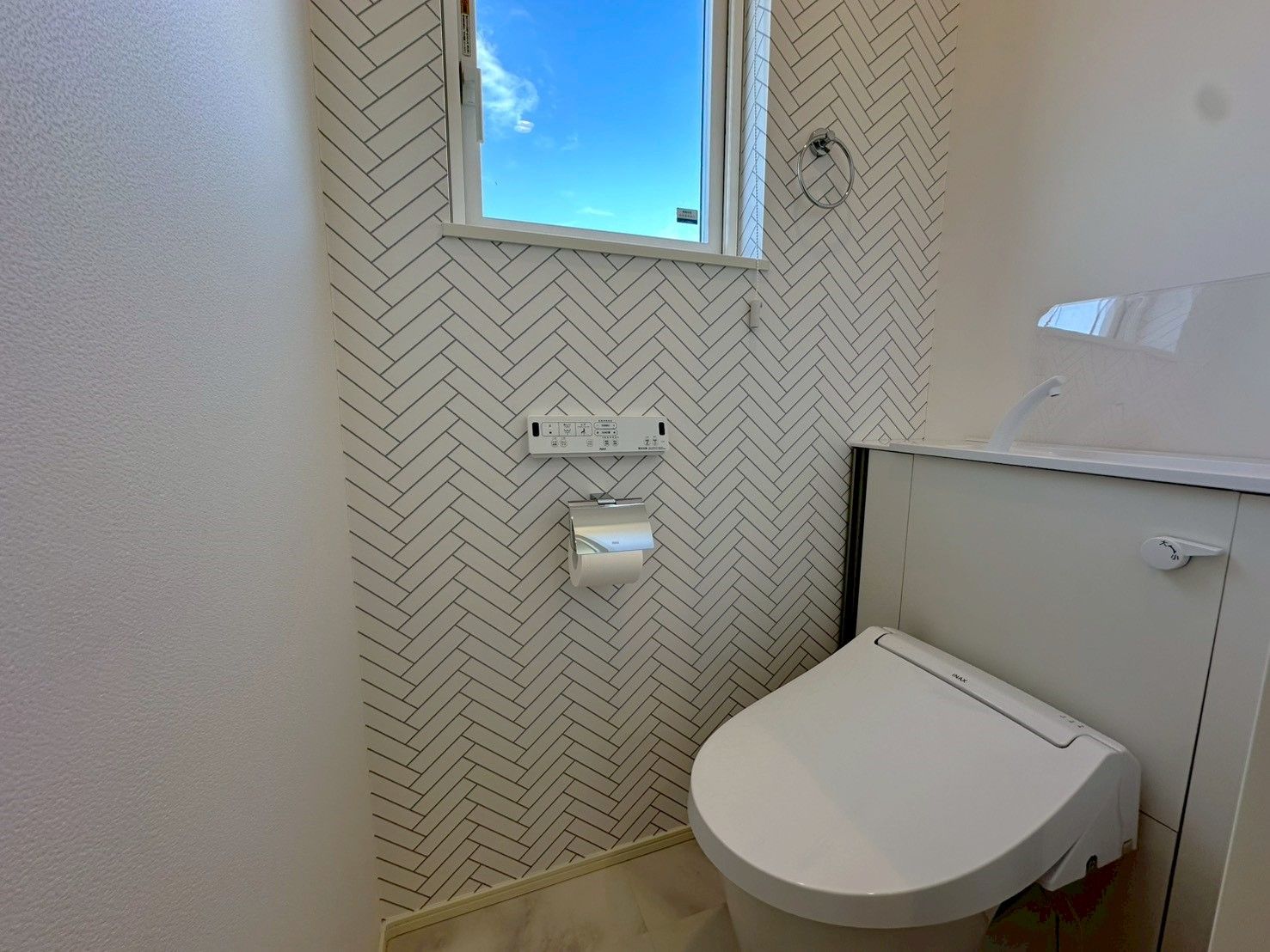 Ein Badezimmer mit einer weißen Toilette, einem weißen Waschbecken und einer Wand mit Zickzackmuster.