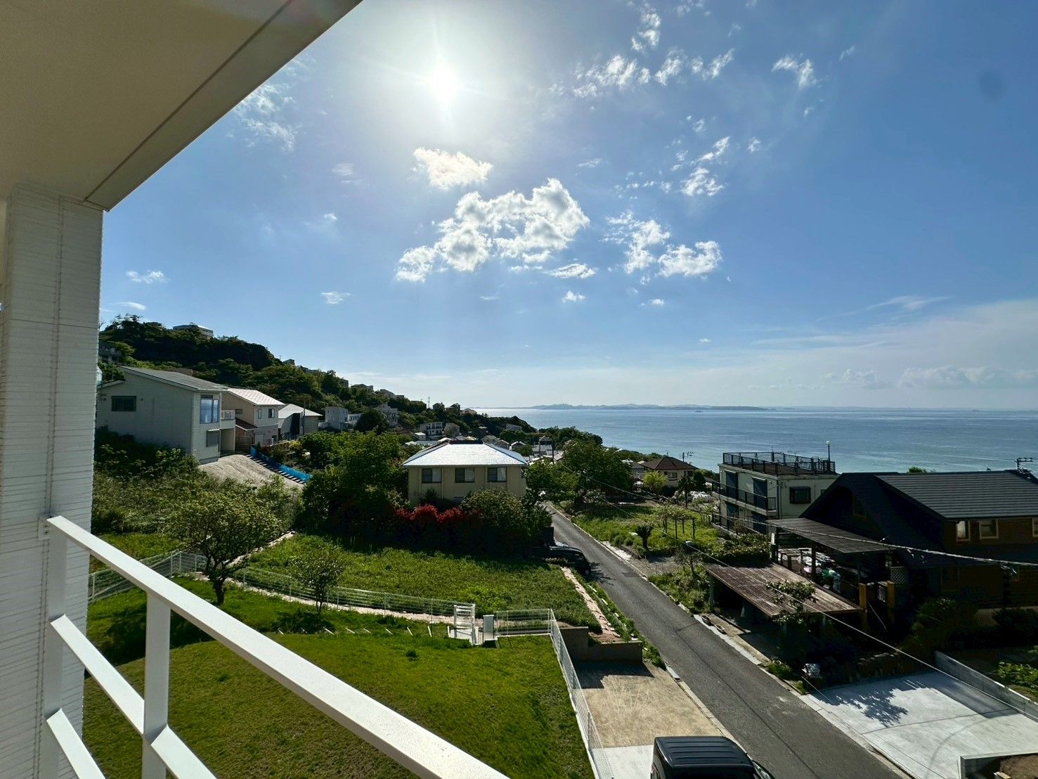 Un quartier résidentiel avec des maisons, une route et une vue sur la mer.