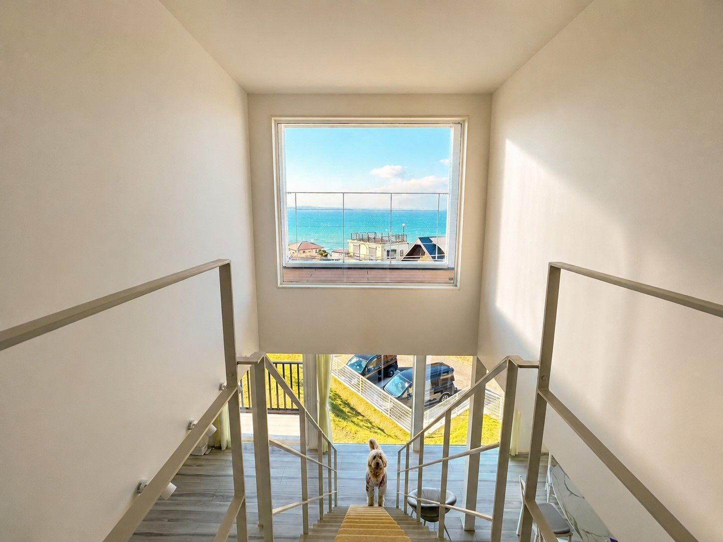 A staircase leading to a balcony with a view of the sea and buildings.