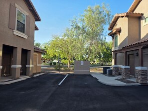 A residential street with houses, a clear sky, and a tree-lined street.