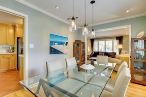 A modern living room with a glass dining table, comfortable seating, and a painting of a boat on the wall. - Near Universities & Hospitals! SLC Home w/ Yard (Salt Lake City)
