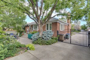 Ein Wohnhaus mit Backsteinfassade, einem großen Baum und einem verschlossenen Einfahrtsweg.
