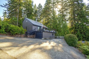 A modern building with a sloped roof, a covered outdoor area with seating, and a gravel driveway. - Hood Canal Views & Near Alderbrook Resort! (Union)