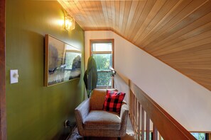 A room with a green wall, a framed picture, a window with blinds, a chair with a red and black checkered pillow, and a wooden ceiling. - Hood Canal Views & Near Alderbrook Resort! (Union)
