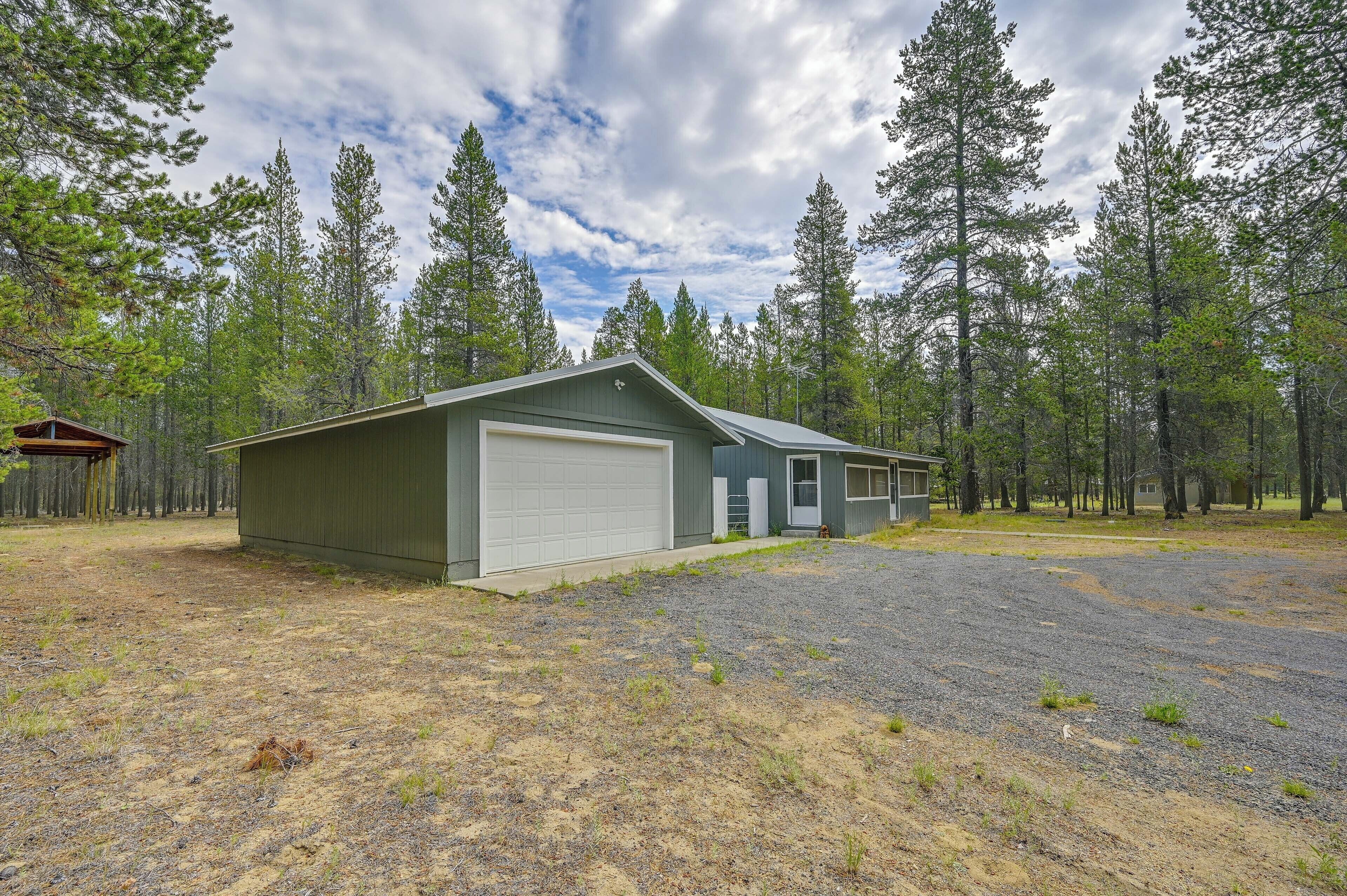 A single-story building with a garage, surrounded by a forested area.