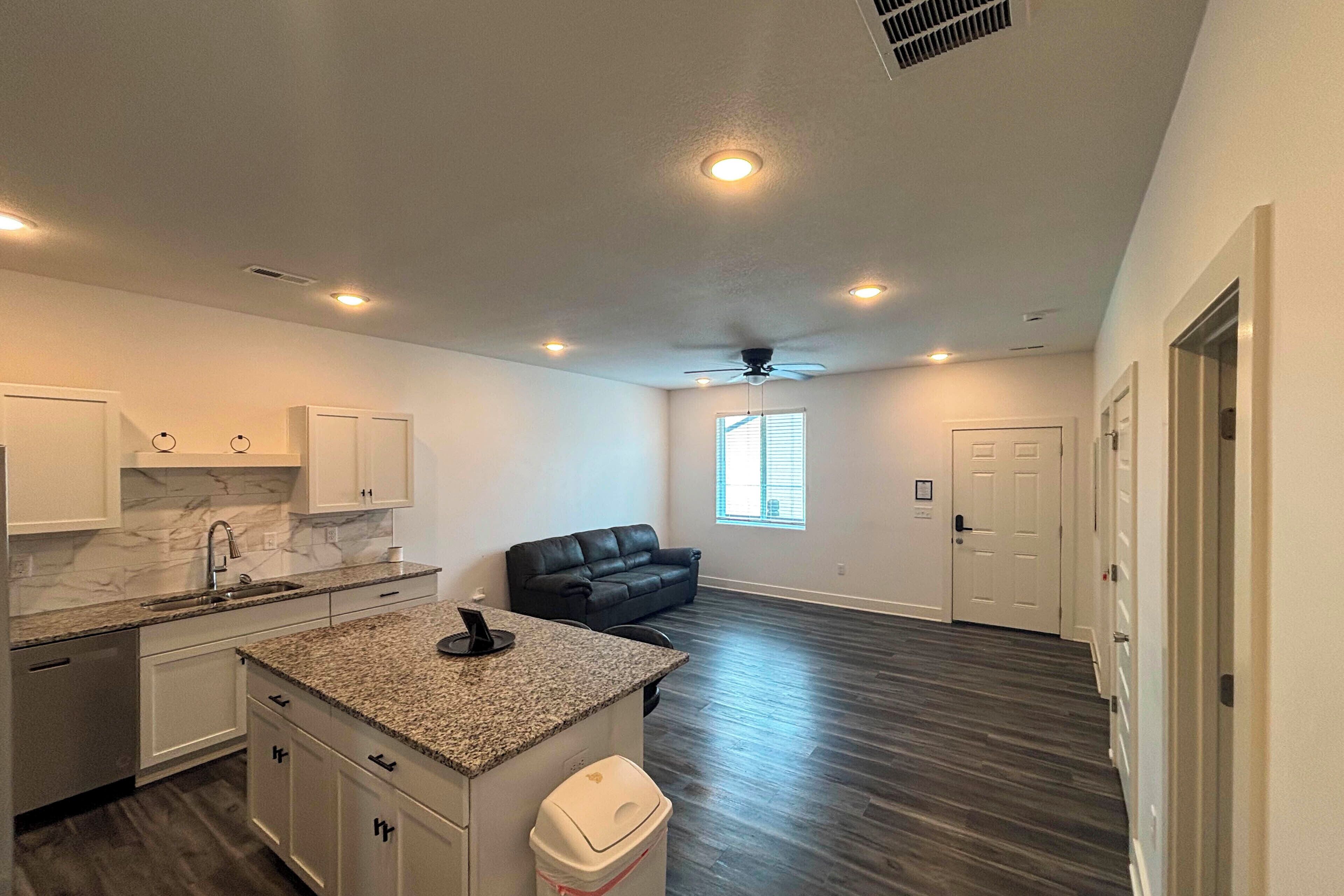 A modern kitchen with granite countertops, white cabinets, and a built-in dishwasher.
