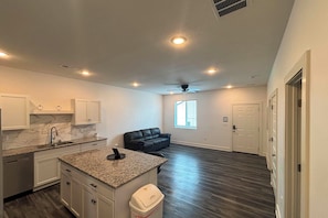 A modern kitchen with granite countertops, white cabinets, and a built-in dishwasher.