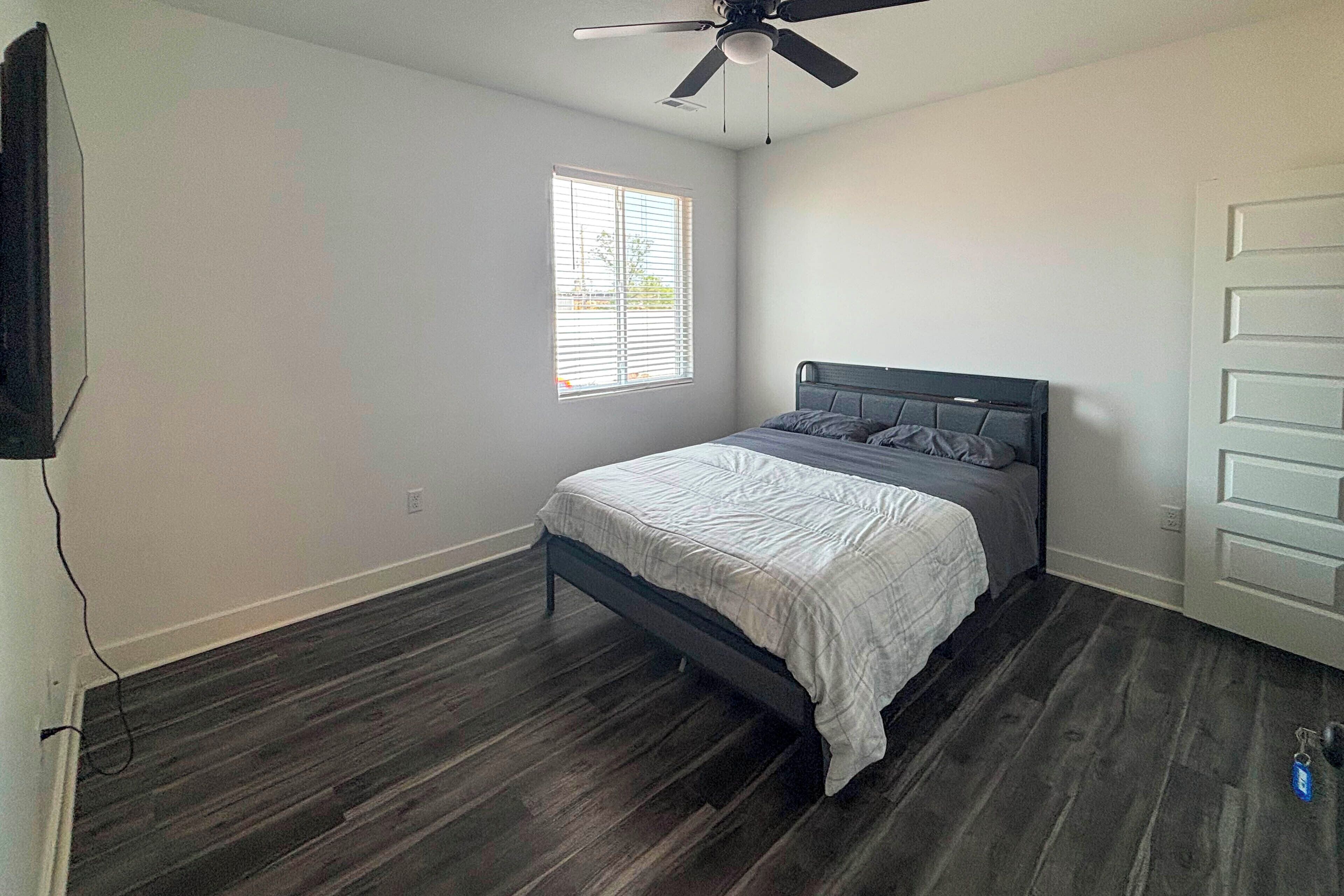 Et soveværelse med en seng, loftventilator, et vindue og en dør.