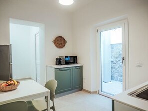 A compact kitchen with a microwave, a basket of fruit, and a view of the outside.