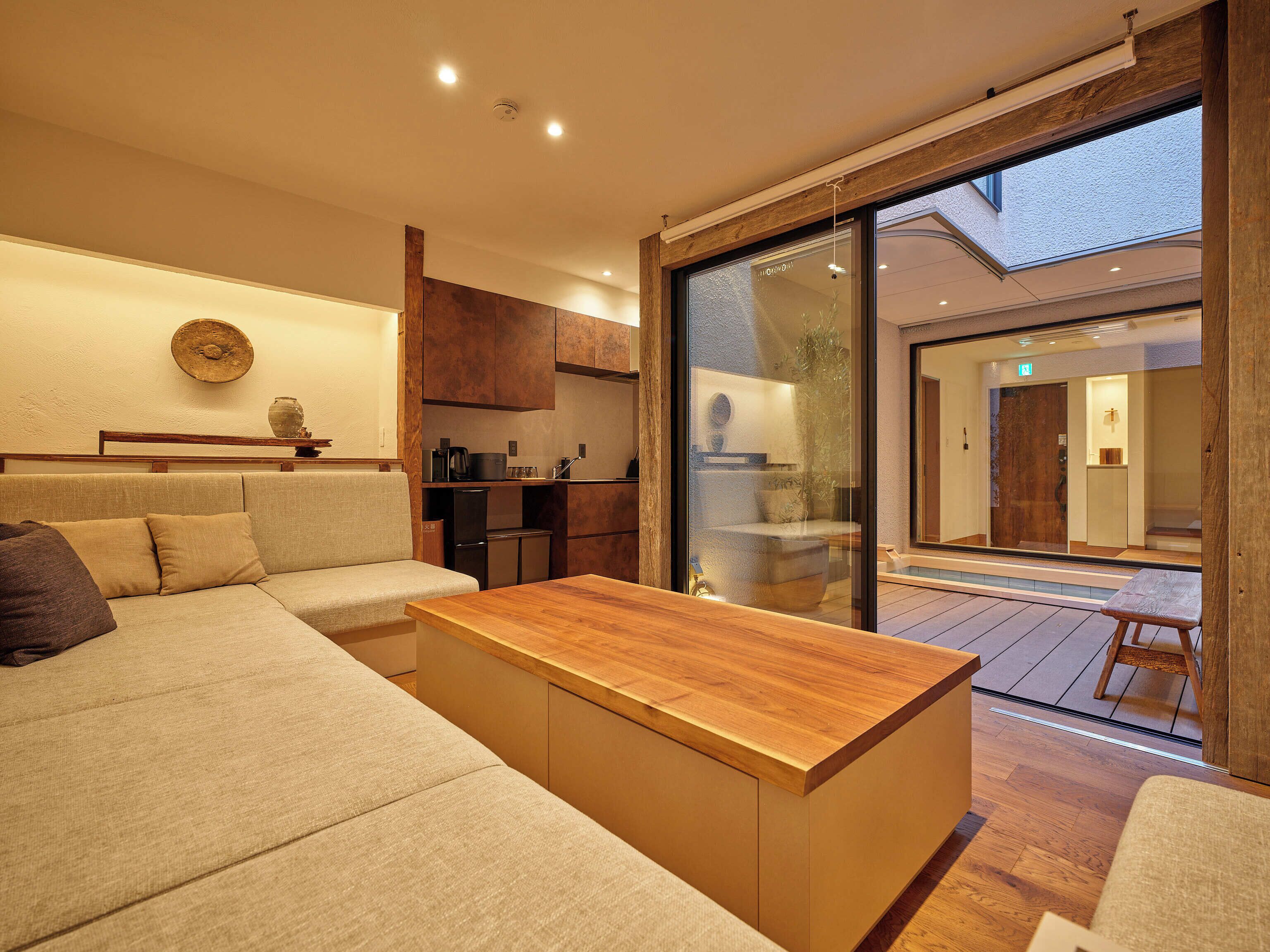 A modern interior with a sofa, wooden table, and a kitchen area.