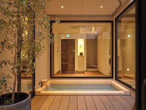 Ein moderner Spa-Bereich mit Holzterrasse, einem gläsernen Whirlpool und einem Blumentopf.