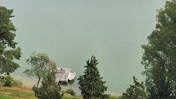 A lake with a dock and a small building, surrounded by dense forest.