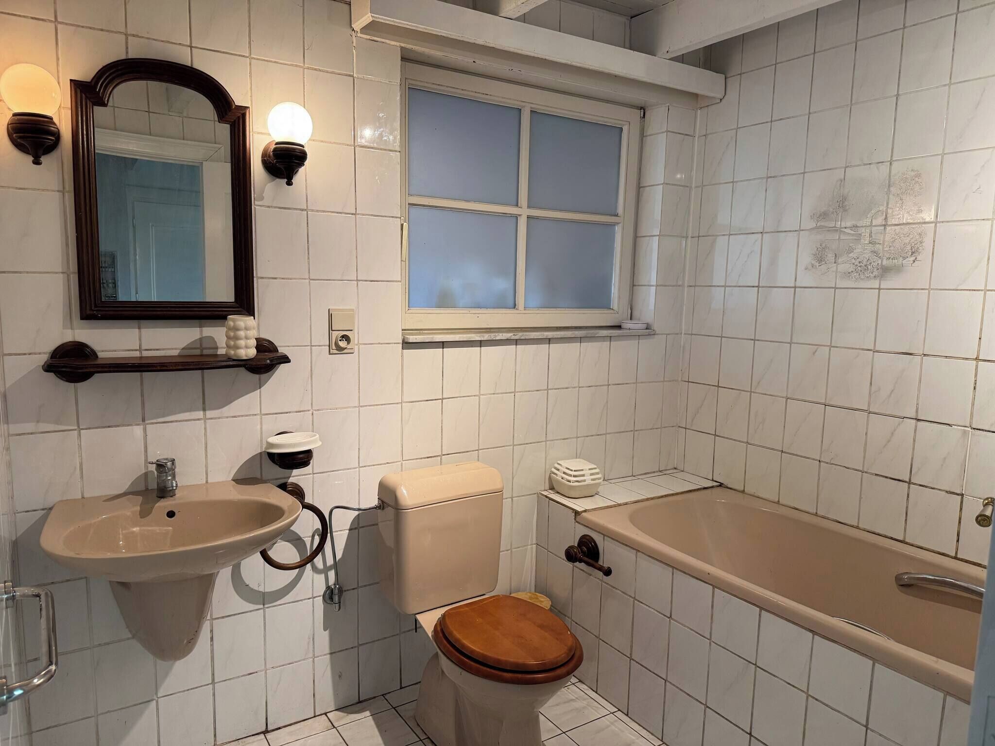Et badeværelse med toilet, vask og badekar.