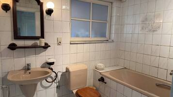 Et badeværelse med toilet, vask og badekar.