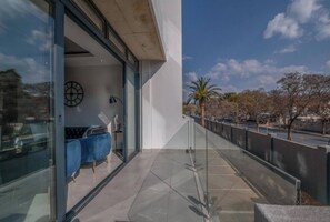 A modern building with a glass entrance, a clock on the wall, and a blue chair outside. - Luxe Houghton Apt The Paramount (Johannesburg)