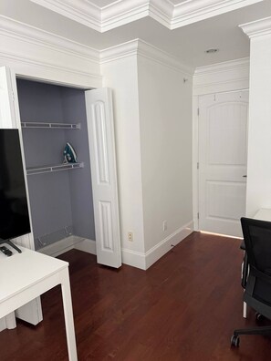 A room with a white door, a television on a white table, and a black office chair. - Master’s Ensuite near Renfrew Skytrain Station (Vancouver)