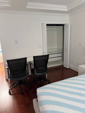 A hotel room with two black office chairs, a bed with a striped bedspread, and a large window with a view of a building. - Master’s Ensuite near Renfrew Skytrain Station (Vancouver)